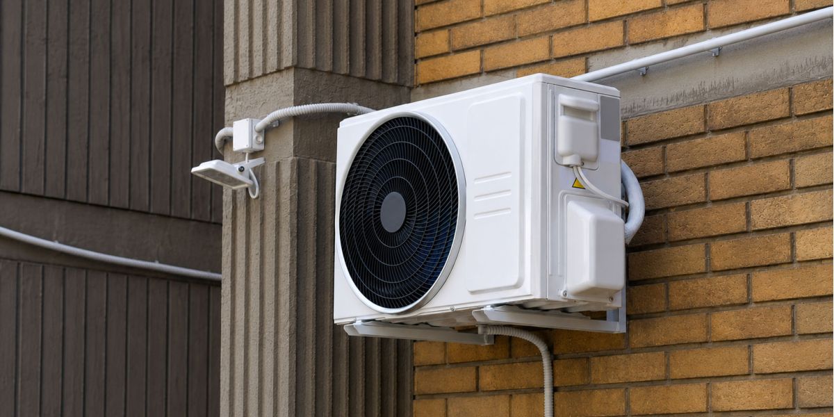 Modern outdoor air conditioning unit installed on a brick house wall, providing energy-efficient heating and cooling for residential properties.